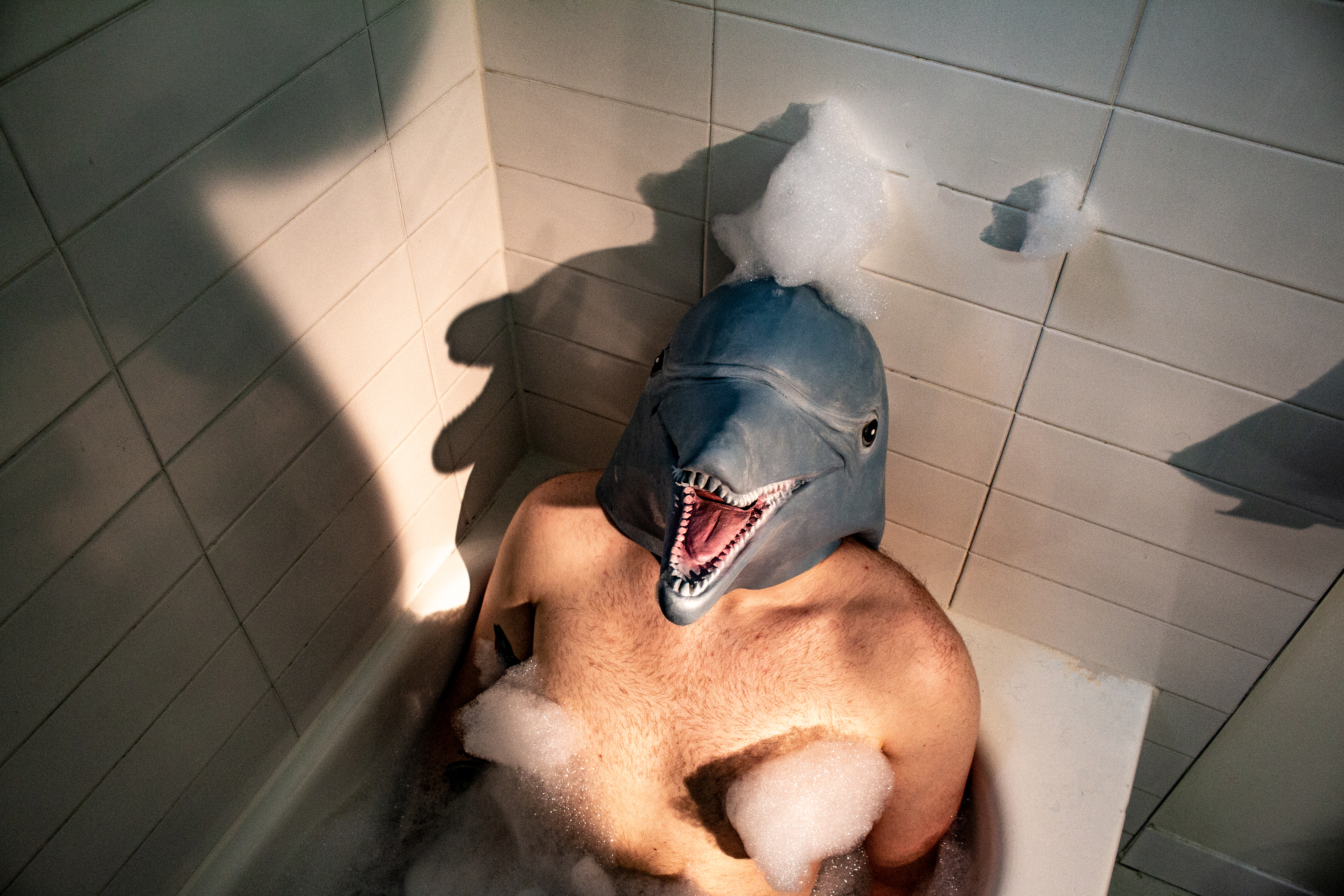 Self-portrait in a bathtub wearing a dolphin mask