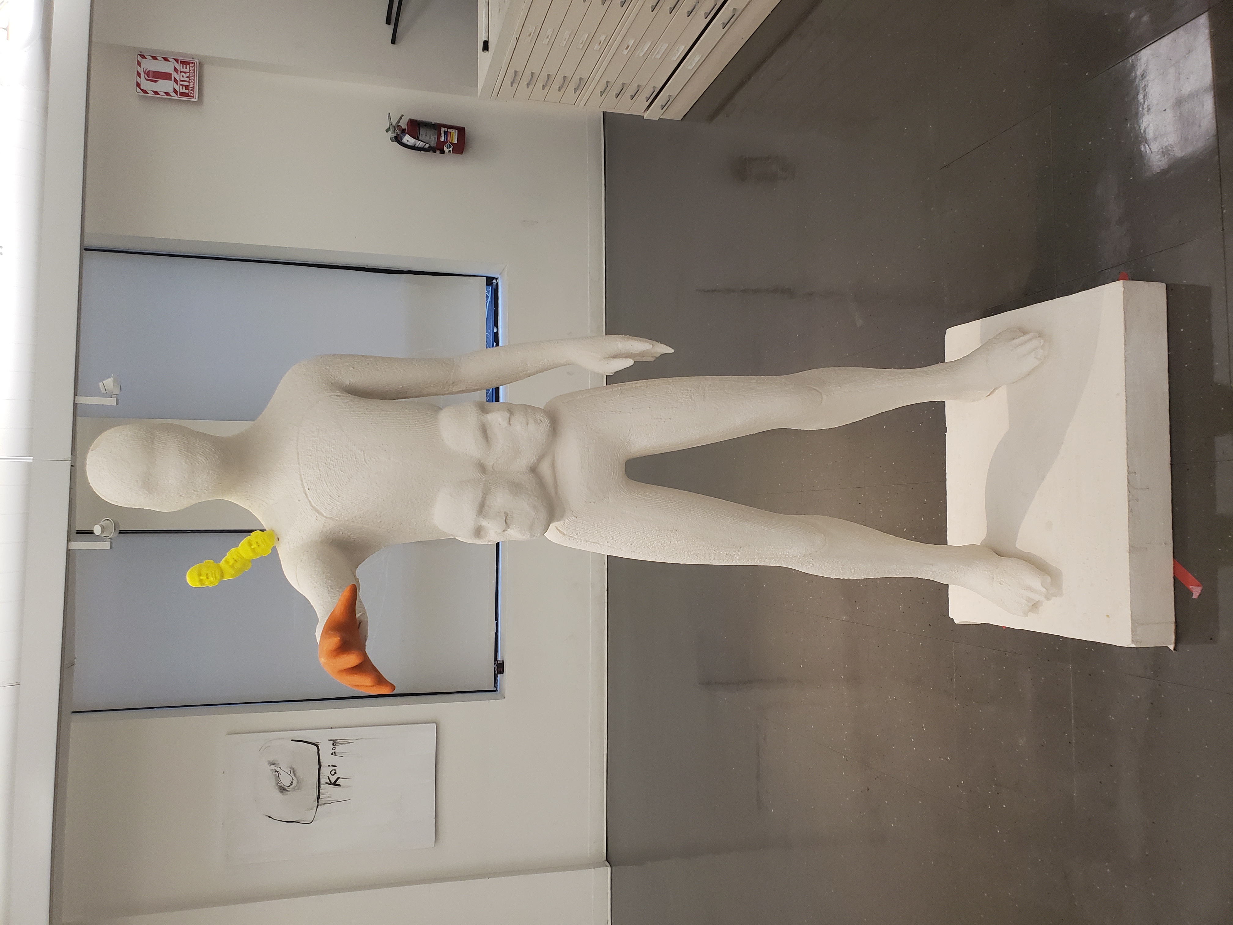 Life-size white foam figure with faces surfacing from its body